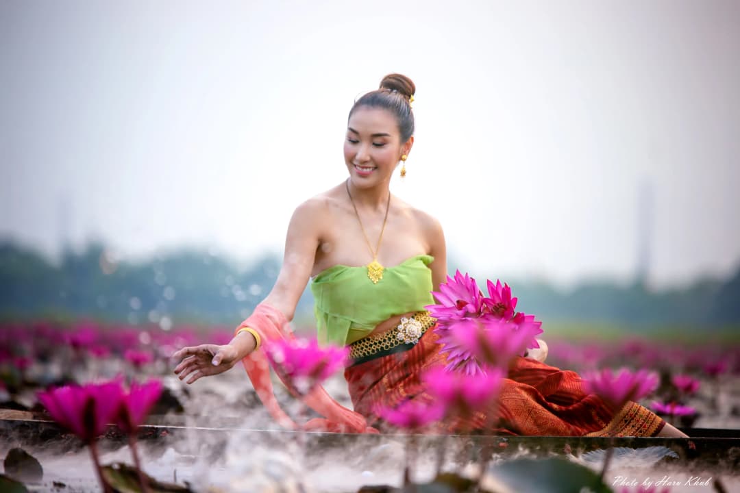Beautiful woman in Thai traditional costume holding pink lotus